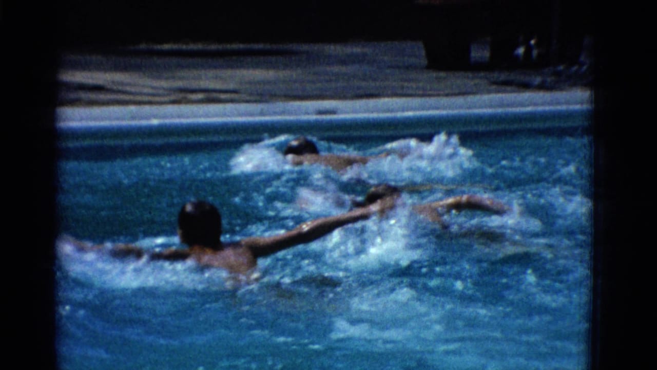 1953 Yonkers 8mm frame showing swimmers in an outdoor pool, with splashing water and a concrete pool edge in the background.