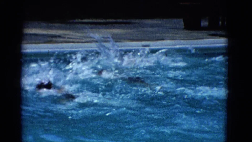 1953 Yonkers 8mm frame with a swimmer partly visible in turbulent pool water during a fast swim or turn.