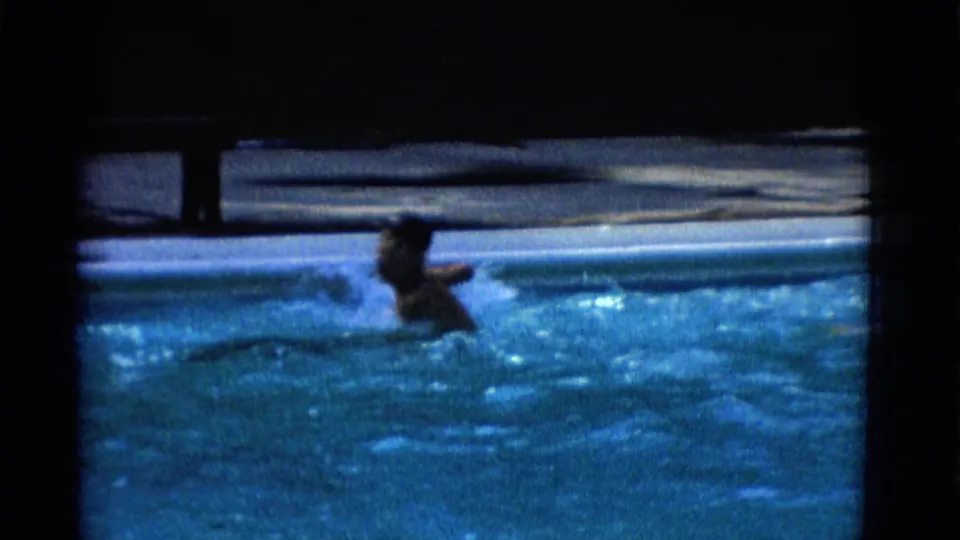 1953 Yonkers 8mm frame showing a swimmer near the pool edge, partially blurred by motion and low exposure.
