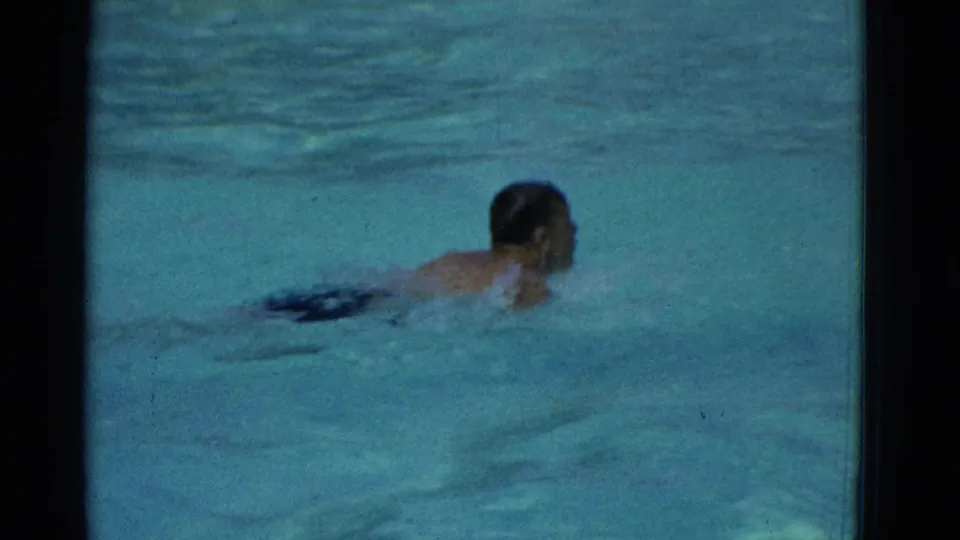 The swimmer's face and upper body briefly rise above the pool surface in the Yonkers 1953 swimming footage.