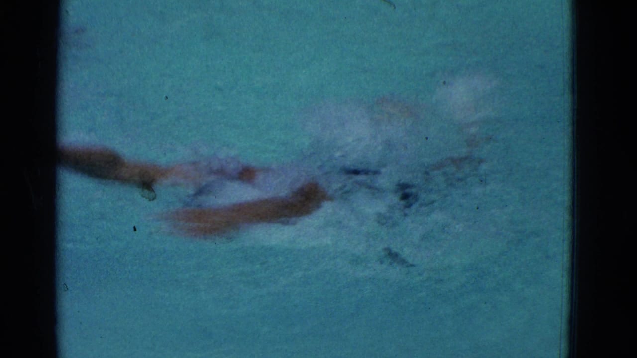 In 1953 Yonkers home-movie footage, a boy swims quickly through a pool with soft focus, splashing water, and blue-green 8mm color.