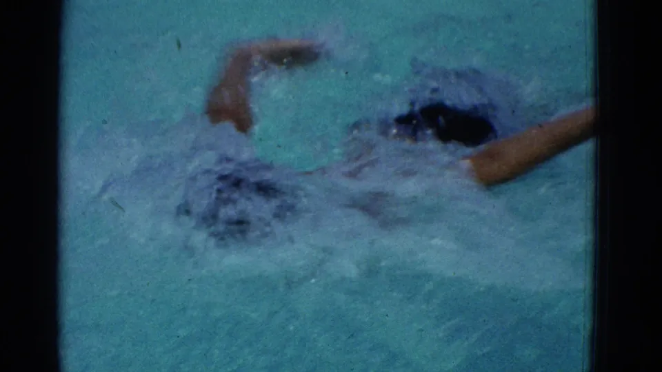 The Yonkers 8mm frame shows the boy mid-stroke in a pool, with one arm forward, one arm rising, and choppy water around him.
