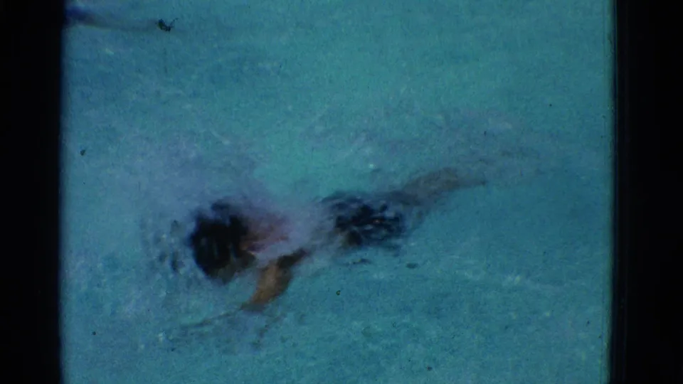 A top-down 8mm view shows the boy mostly submerged during the swim, with his head and arms partly visible beneath choppy pool water.
