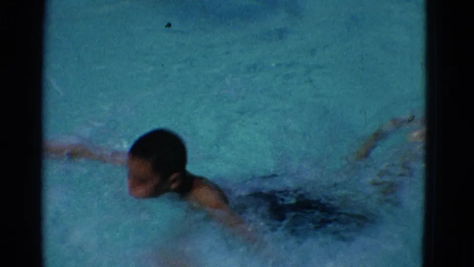 The final sampled frame shows the boy's face in profile above the pool surface as he swims forward through blue-green water.