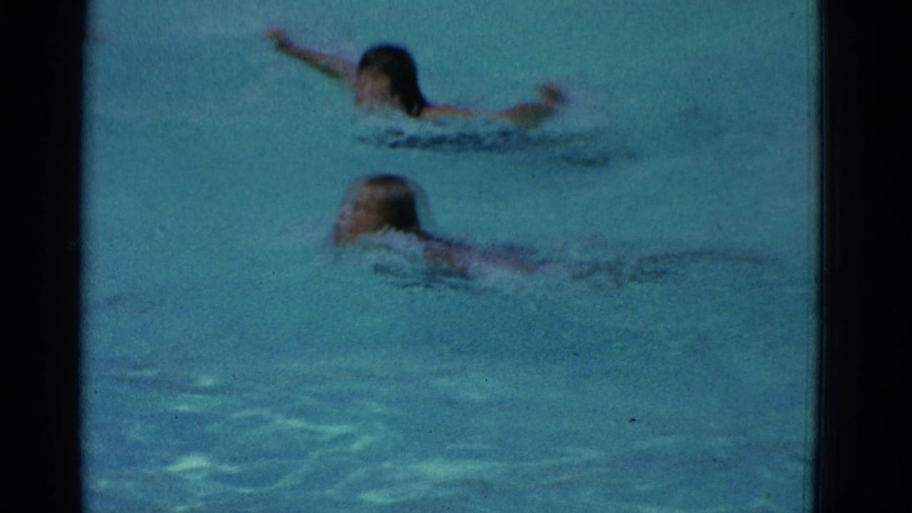 Two swimmers move across blue pool water as an 8mm frame border surrounds the scene.