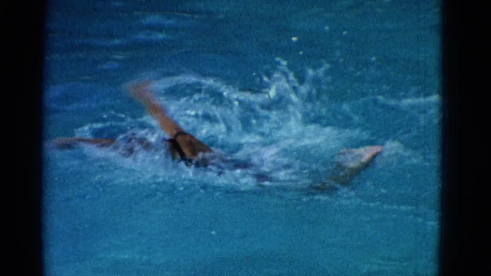 Near the end of the Yonkers swimming clip, a swimmer’s arm and head break through churning blue water in a grainy 8mm frame.