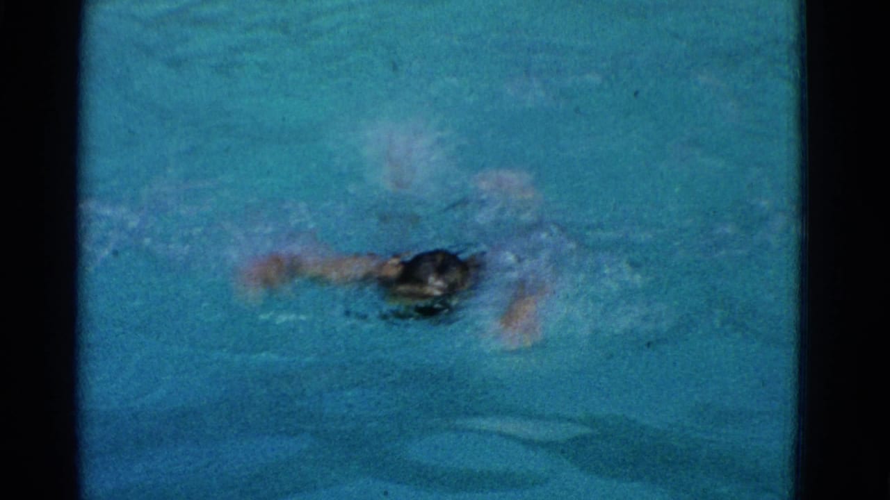 Swimmer partly turned in blue pool water with one arm extended and splashing.