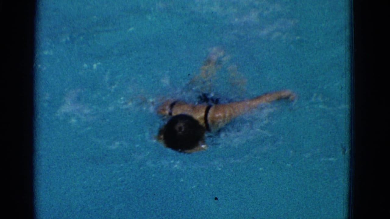 1953 Yonkers 8mm frame showing a young swimmer moving through blue pool water with one arm extended and bubbles around the body.