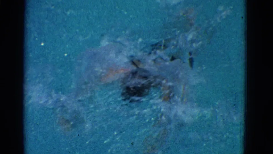 1953 Yonkers 8mm frame with the swimmer mostly obscured by blue water, splash, and bubbles during a forceful stroke.