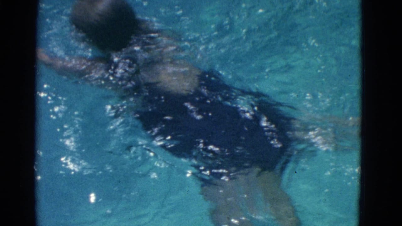 A swimmer in a purple bathing suit moves through blue pool water in 1953 Yonkers home-movie footage.