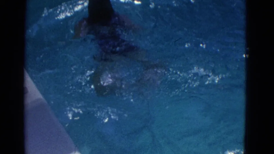 A swimmer in a purple suit is visible through darker blue pool water near the frame edge.