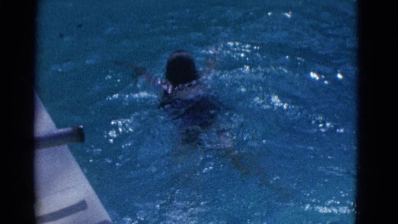 1953 Yonkers 8mm frame showing a swimmer moving away through a backyard pool with splashing water and film borders.