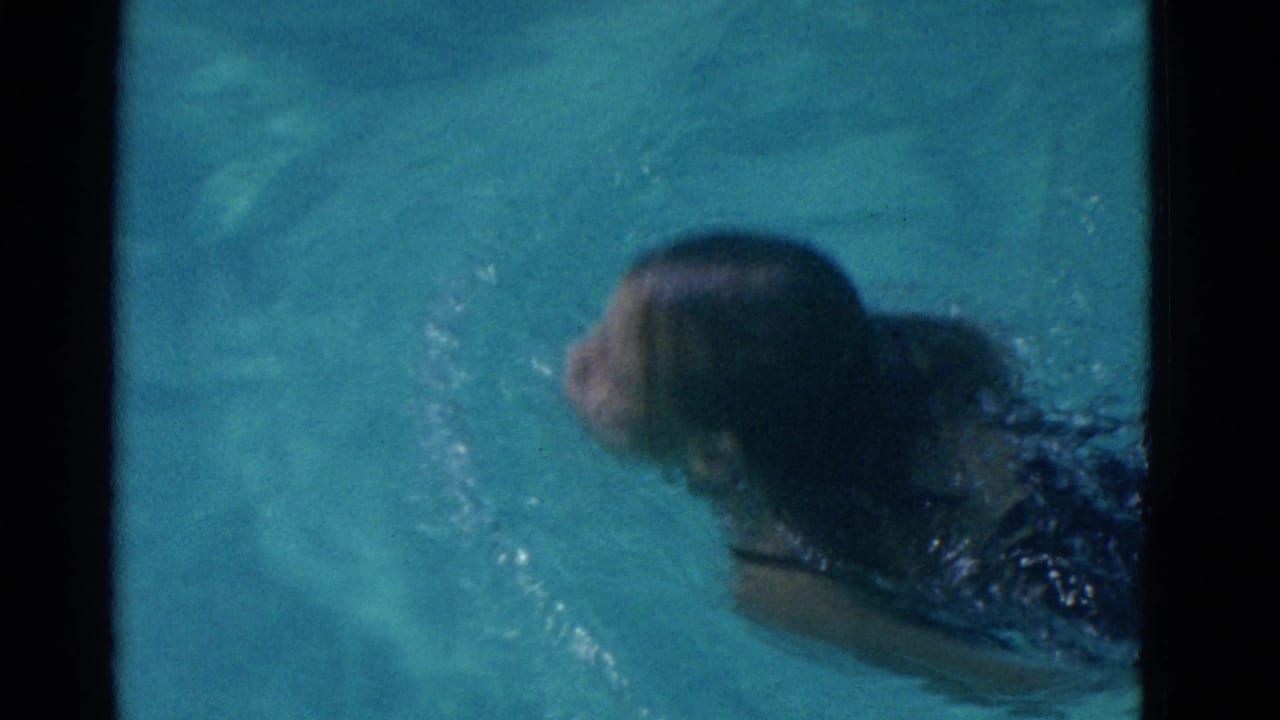 Swimmer moving through blue pool water with head near the surface.