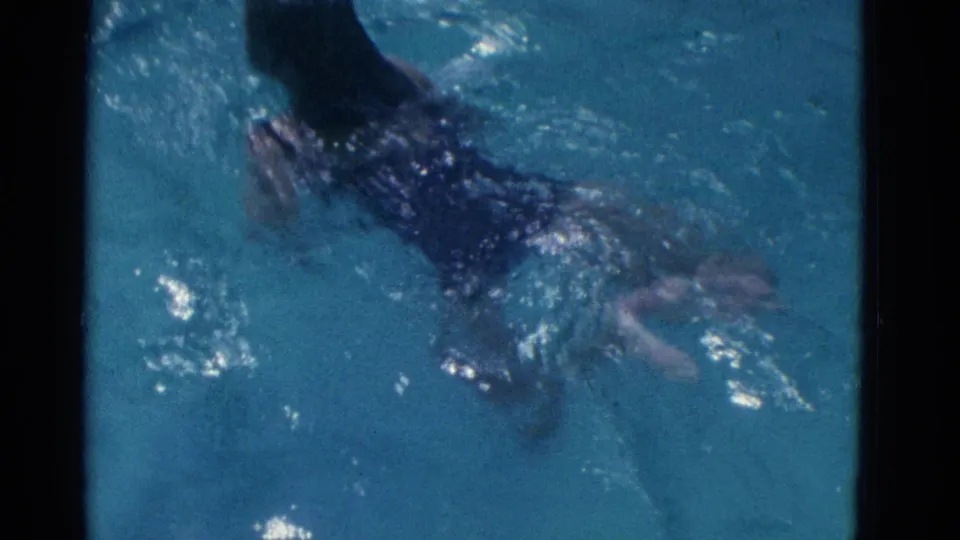 A likely young swimmer is partly submerged during a breaststroke motion in 1953 Yonkers pool footage.