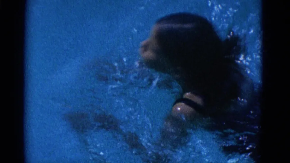 The 1953 Yonkers pool footage shows the swimmer turning in the water, with face profile, wet hair, shoulder, and ripples visible.