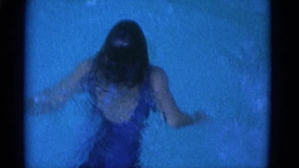 A woman in a blue swimsuit swims through blue-tinted water in 1953 8mm home-movie footage from Yonkers, New York.