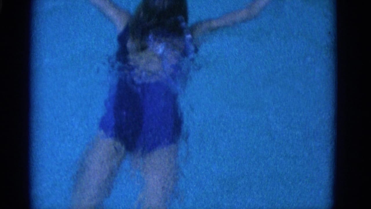 1953 Yonkers 8mm frame showing a swimmer in a dark one-piece suit moving through blue pool water from an overhead view.
