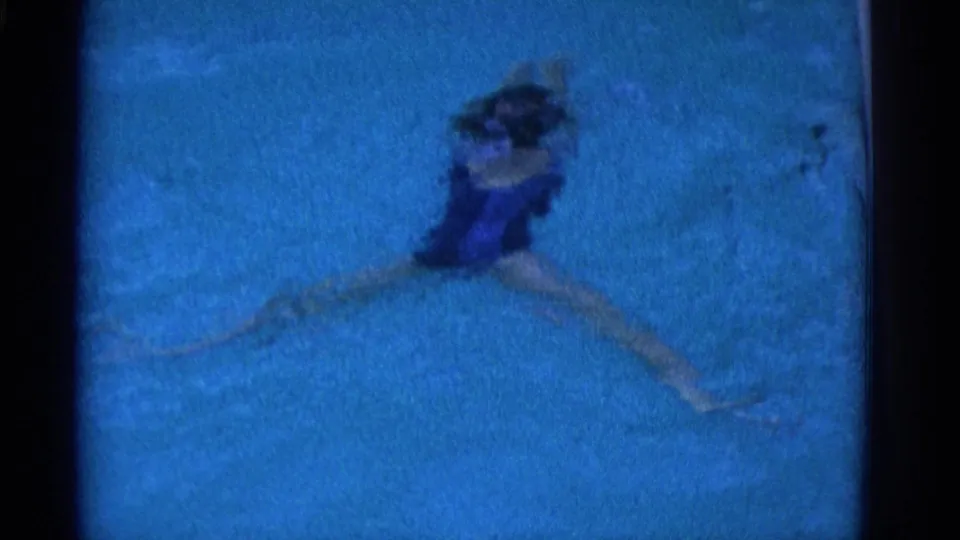 1953 Yonkers 8mm frame with the swimmer spread across the blue pool, legs extended and dark hair visible near the surface.