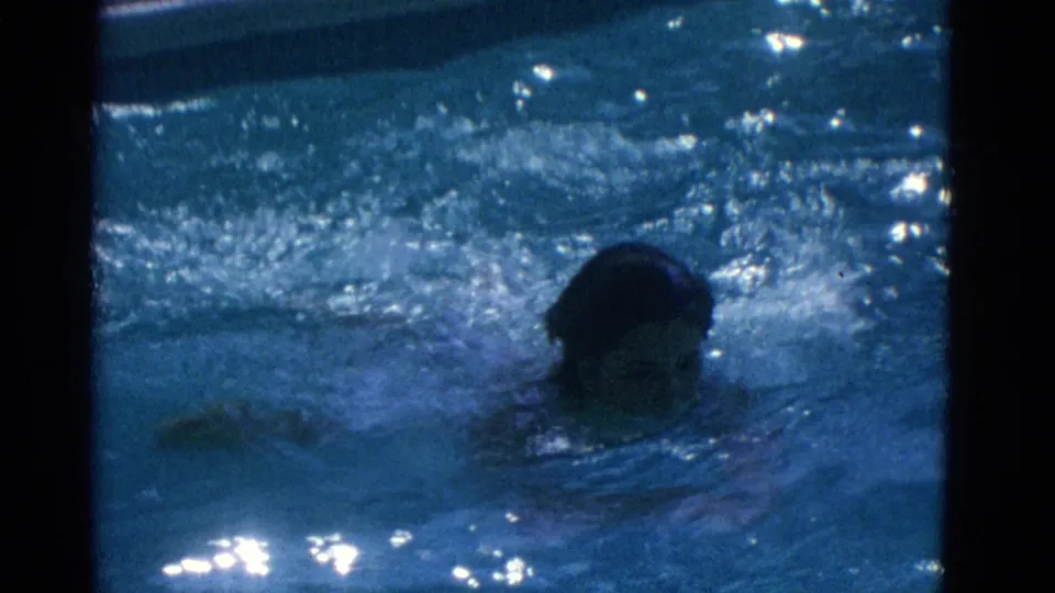 1953 Yonkers 8mm frame with a swimmer's head above rippled blue pool water during a breaststroke sequence.