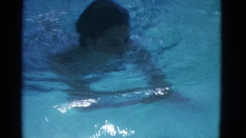 1953 Yonkers 8mm frame showing a swimmer close to the camera, face partly visible as arms move through the pool.
