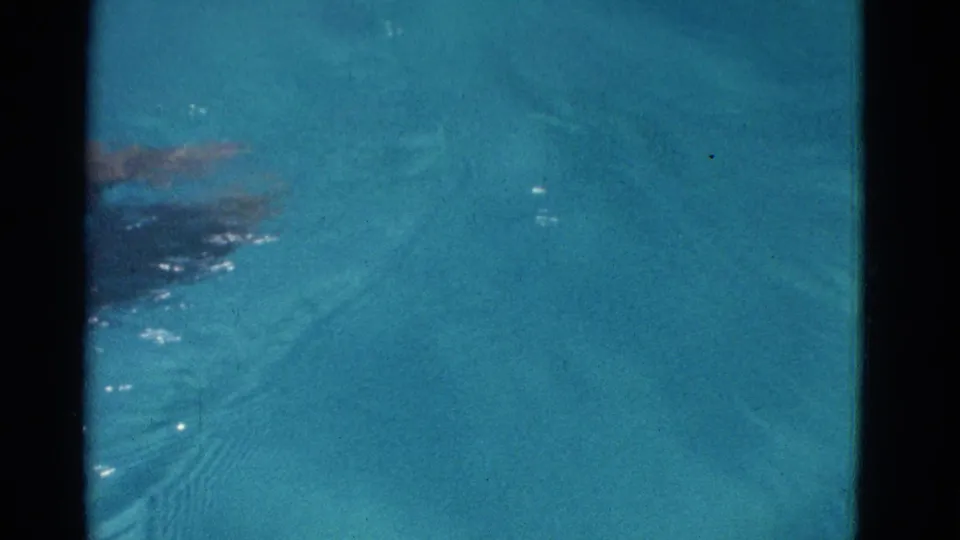 1953 Yonkers 8mm frame showing an underwater arm and body movement in clear blue pool water near the end of the stroke.