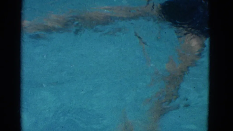 A partially submerged swimmer appears through rippled turquoise water in this 1953 Yonkers 8mm home-movie frame.