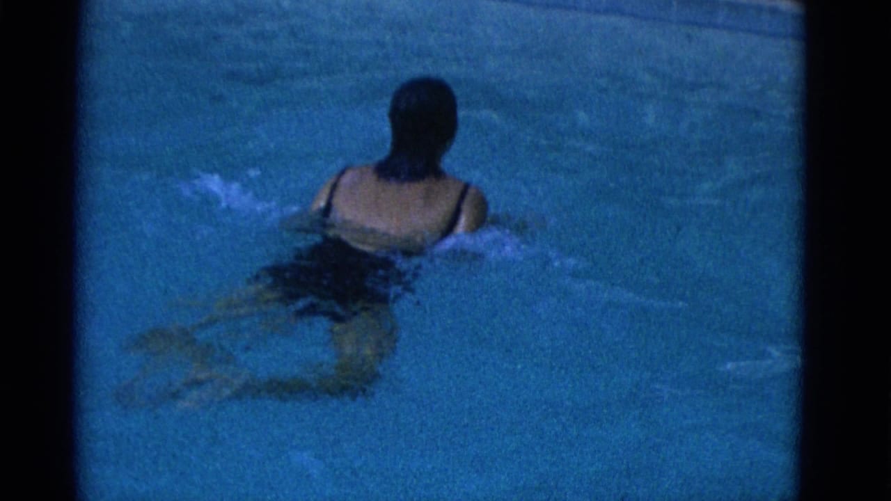In 1953 Yonkers home-movie footage, a woman in a dark one-piece swimsuit swims away from the camera in a pool.