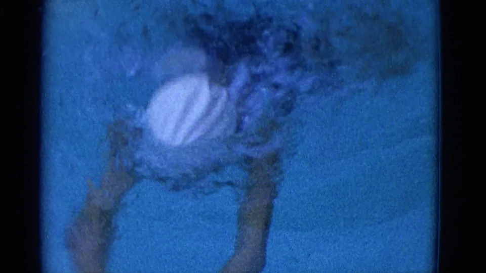 Underwater 1953 Yonkers frame showing the swimmer in a white cap and dark bathing suit mid-breaststroke, partly obscured by bubbles.