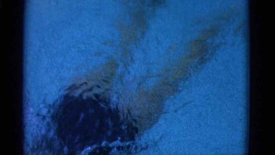 Underwater home-movie frame from Yonkers in 1953 showing the swimmer partly below frame while kicking through blue pool water.