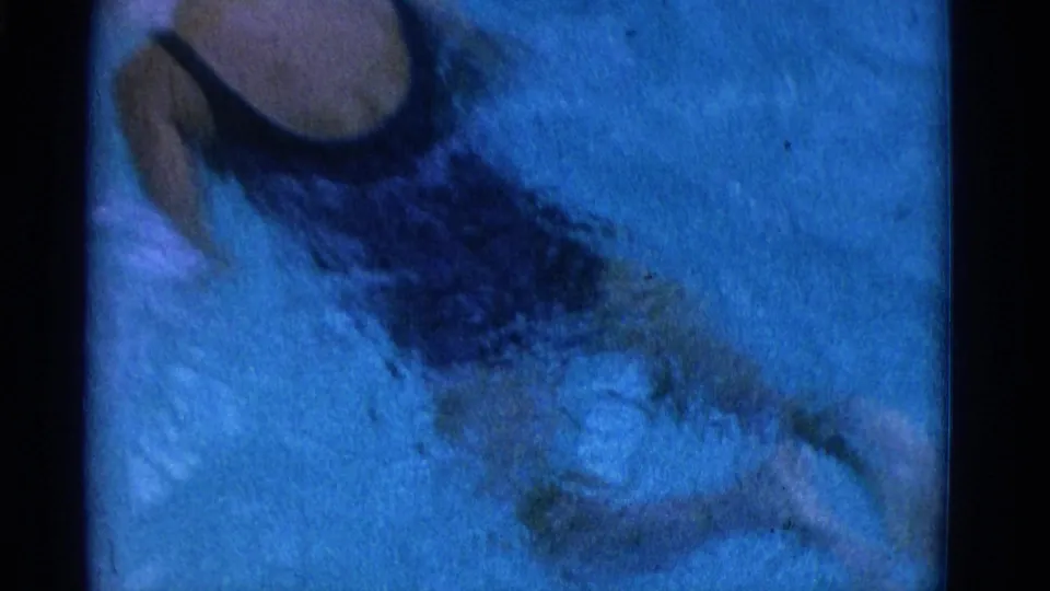 1953 Yonkers pool frame with the swimmer partly submerged, white cap visible, and blue-tinted water filling the view.