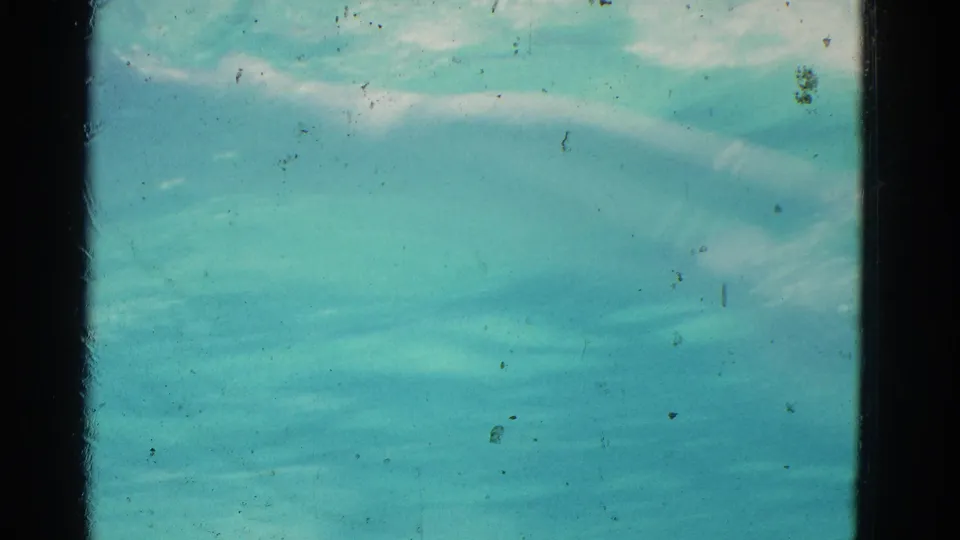 1953 Yonkers 8mm frame with rippling turquoise water, bright reflected streaks, grain, dust, and contact-sheet borders.