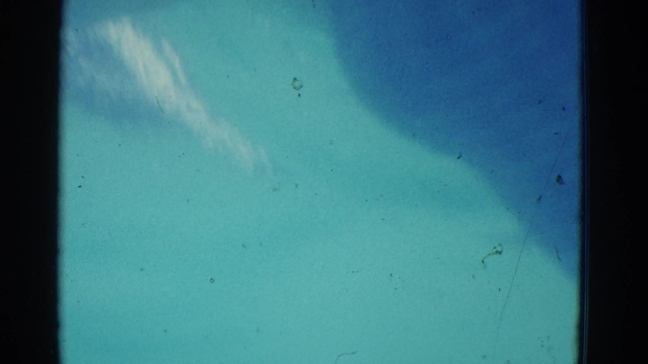 1953 8mm Yonkers home-movie frame showing abstract blue-green pool water, soft underwater light, dust, scratches, and dark gate edges.