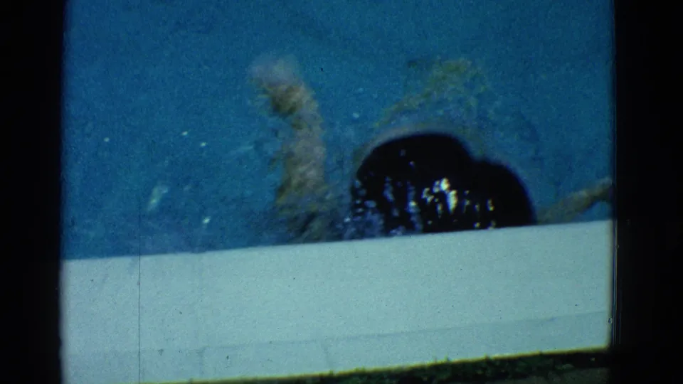 1953 Yonkers frame showing the swimmer near the white pool edge, with splashing water and 8mm film texture visible.