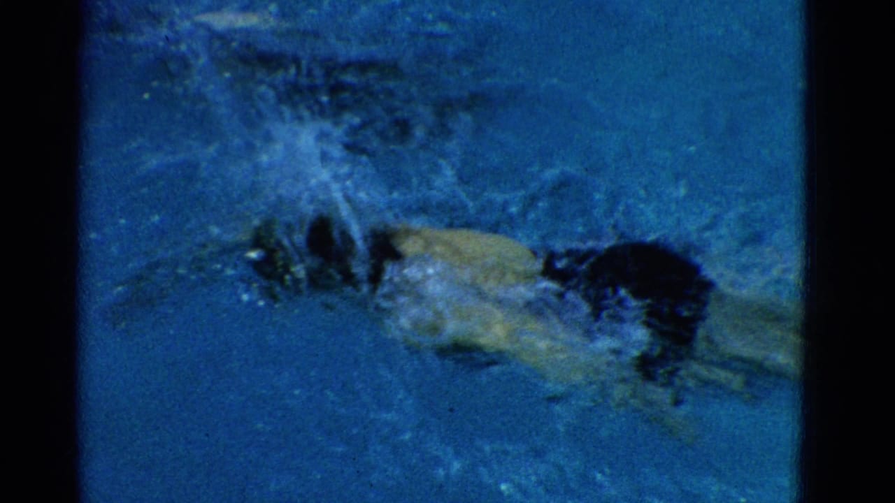 Swimmer moving underwater near the pool surface with bubbles and blue water.