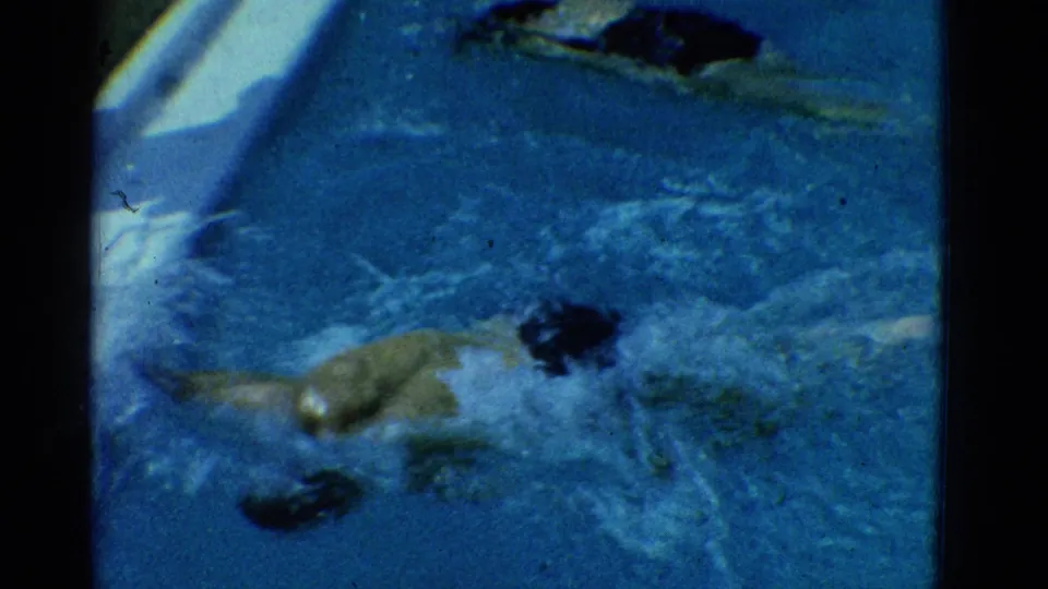1953 Yonkers pool footage showing a swimmer turning through churning water near a pale pool edge.