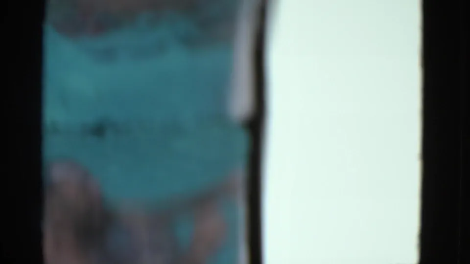 Blurred 1953 home-movie frame showing turquoise pool water and an indistinct partial body near the lower edge.