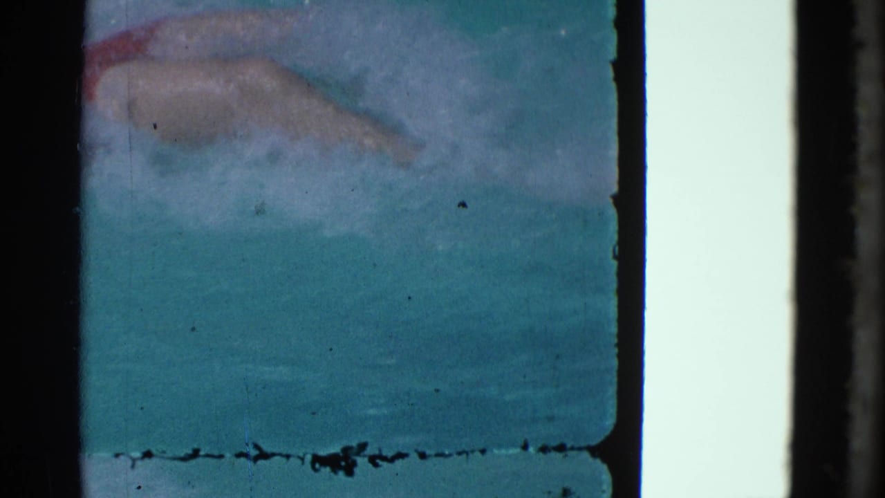 Blue-green underwater frame with a faint submerged shape and visible film border.