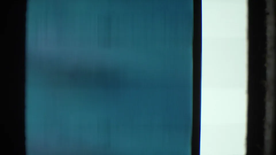 Abstract 8mm scan frame from the Yonkers clip, dominated by blue-green film texture and vertical frame-edge bands.