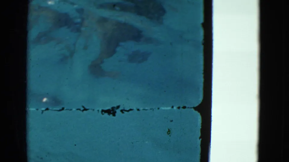 1953 Yonkers underwater home-movie frame with a blurry submerged shape, scratches, dust, and dark 8mm frame edges.