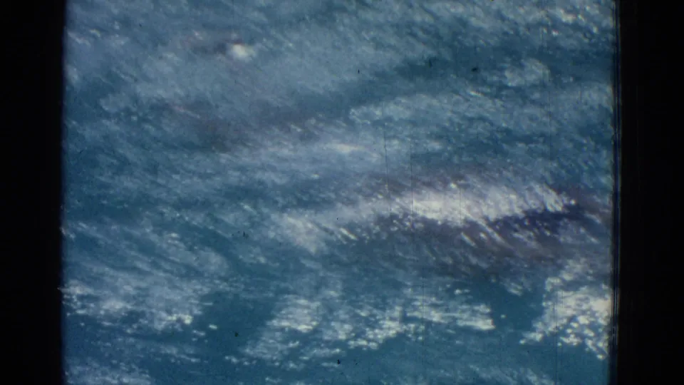 Sunlit, choppy pool water fills the frame, with the swimmer partly obscured beneath the rippling surface in the Yonkers home movie.