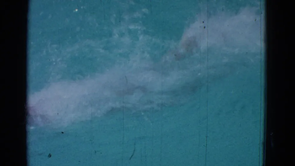 Blue-green 8mm pool frame from the Yonkers clip, with a swimmer mostly obscured by water and motion blur.