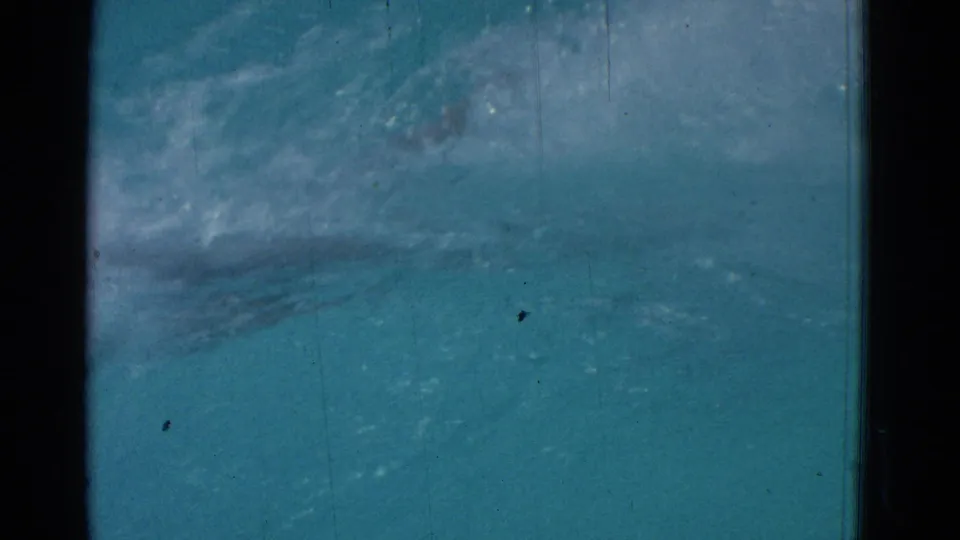1953 8mm frame showing underwater movement in a Yonkers pool, with the swimmer partly obscured by bubbles and teal water.