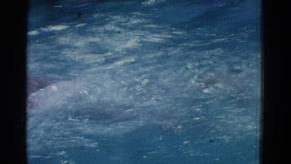 Blue public-pool water ripples across the frame as a swimmer’s body is partly visible near the bottom edge.