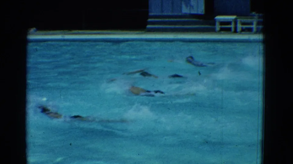 The swimmers continue across the Yonkers pool in 1953, seen in soft 8mm color with splashes spreading across the water surface.