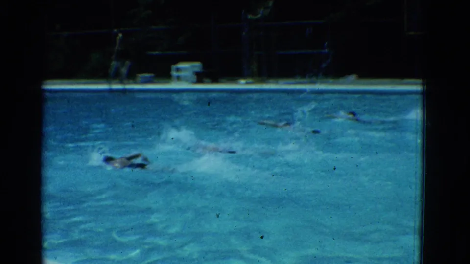 By the end of the 1953 Yonkers clip, swimmers near the opposite side of the outdoor pool while the deck and background structures remain visible.