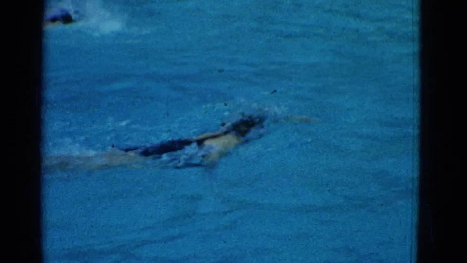 1953 Yonkers pool footage showing a swimmer moving through blue water with visible 8mm grain and dark frame edges.