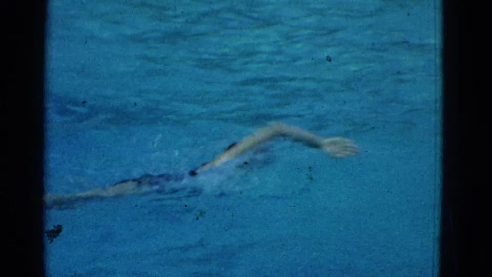 A swimmer in the Yonkers pool extends an arm during a freestyle stroke in grainy 1953 8mm footage.