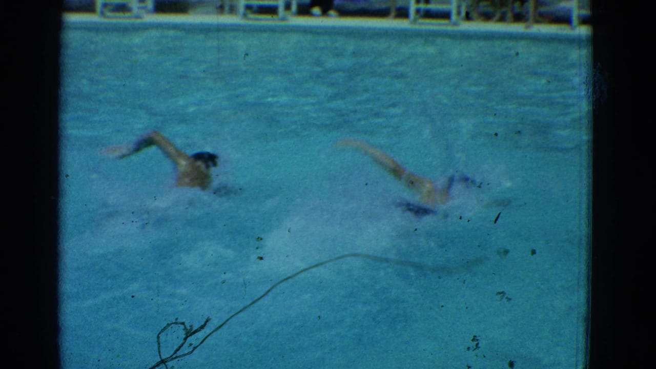 Two swimmers appear mid-stroke in a Yonkers pool, filmed on 8mm home-movie footage from 1953.