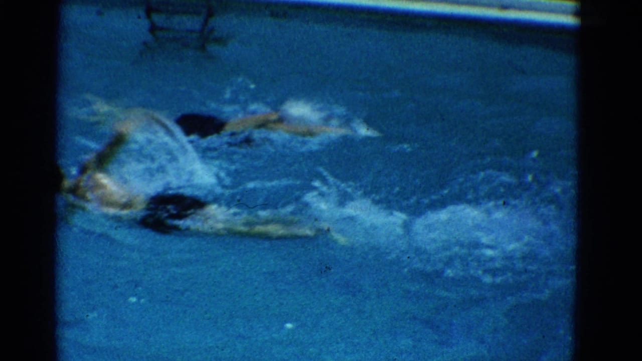 Swimmer in a white cap moves through blue pool water with splashes around the arms.