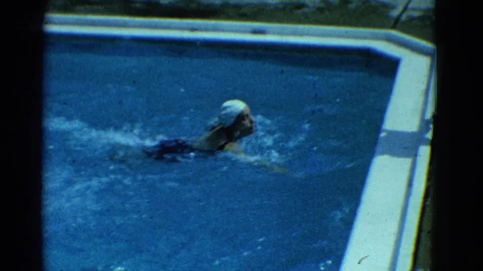 1953 Yonkers frame with a white-capped swimmer seen in profile during a backyard pool lap.